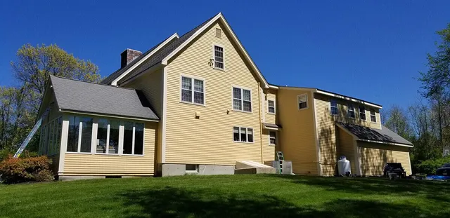 The side exterior view of a large yellow house.