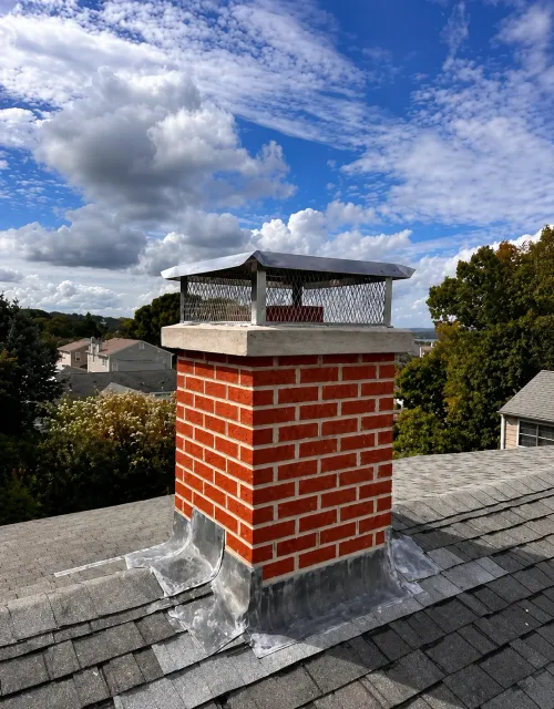 Close-up of a stainless steel chimney cap installed on a chimney crown