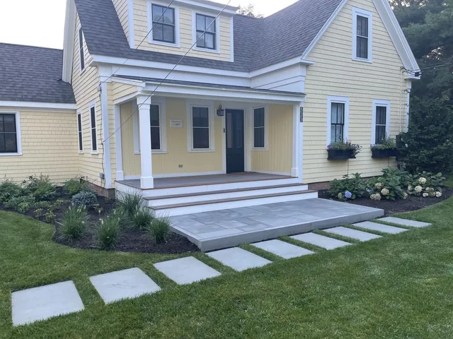 Bluestone patio with fieldstone walls and integrated planting beds on a Cape Cod estate by Blue Claw Associates