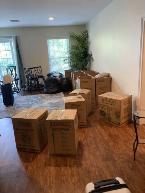 Boxes and bags in a room, hardwood floor, window with light, moving.