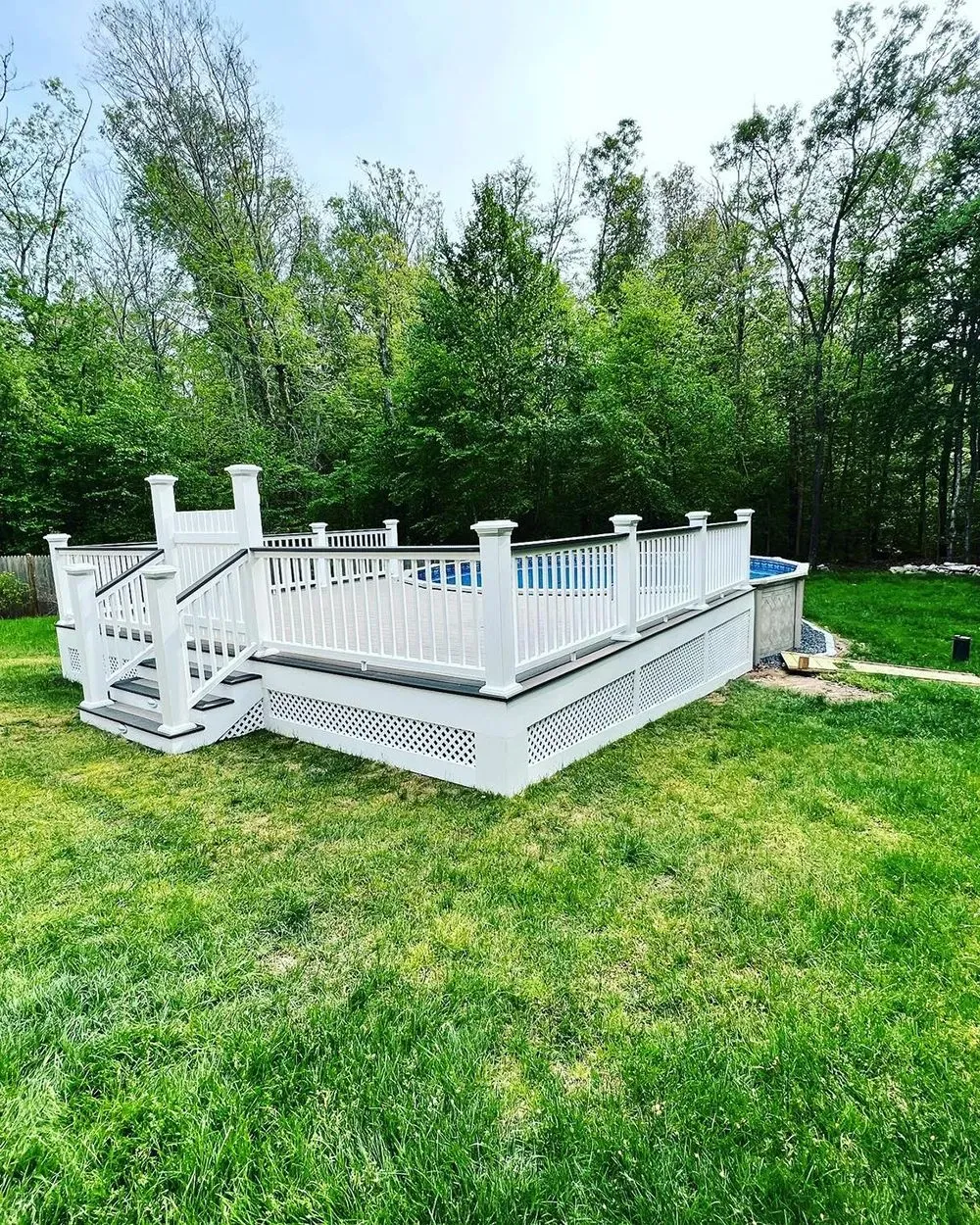 A white deck with stairs and a pool in the backyard