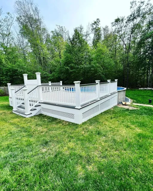 A white deck with stairs and a pool in the backyard