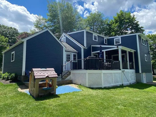 A blue house with a white deck and a playhouse in front of it.