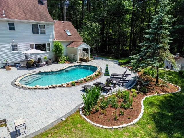 There is a large swimming pool in the backyard of a house.