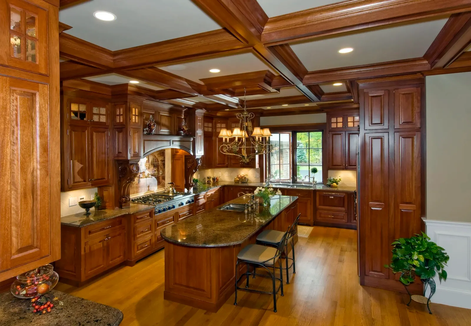 Traditional kitchen with dark wood cabinets, granite countertops, chandelier, and large window overlooking garden.