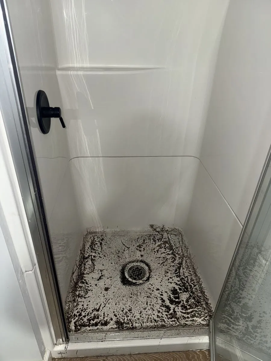 Shower base darkened by buildup before cleaning