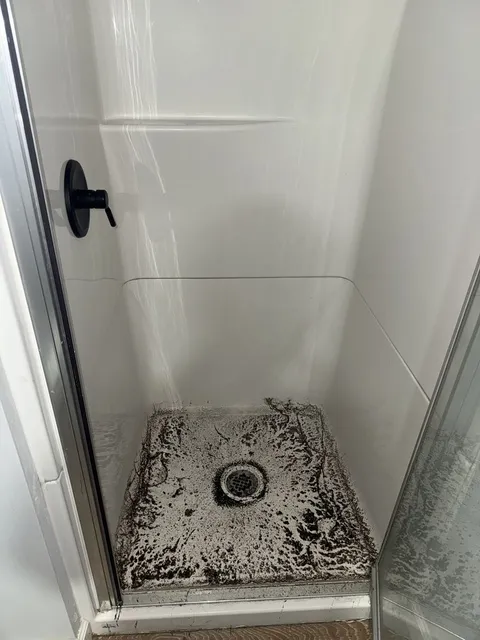 Shower base darkened by buildup before cleaning