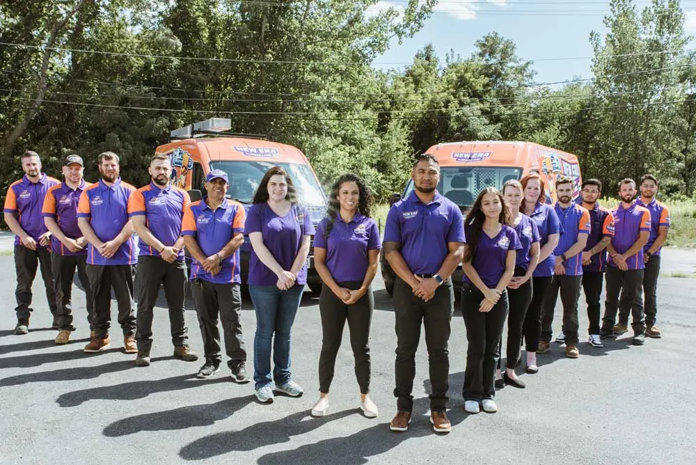 New Era's team poses outside in front of two service vans