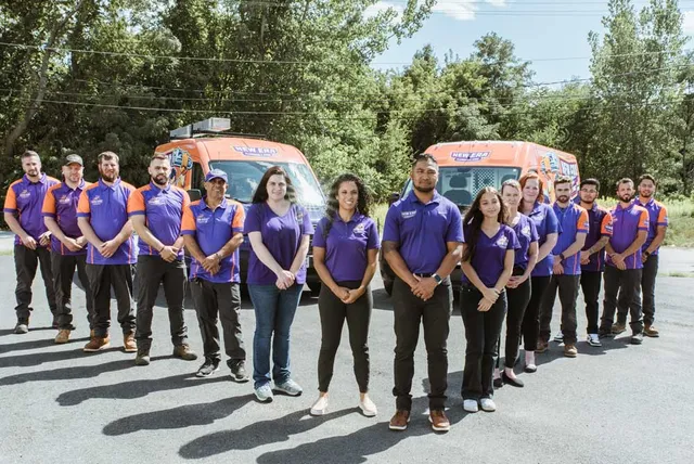 New Era's team poses outside in front of two service vans