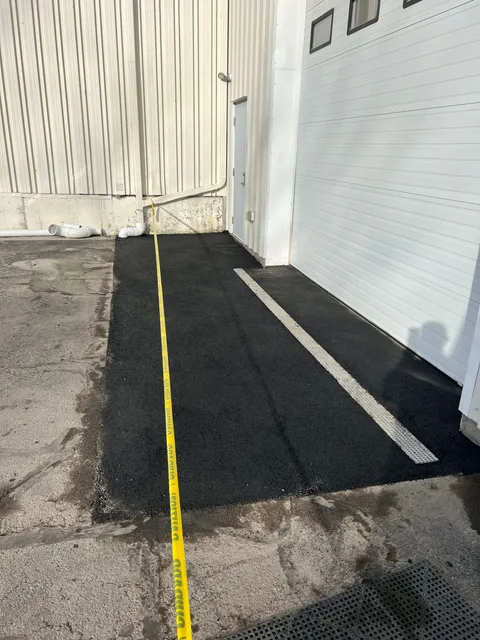 A yellow tape measure is laying on the ground next to a garage door.