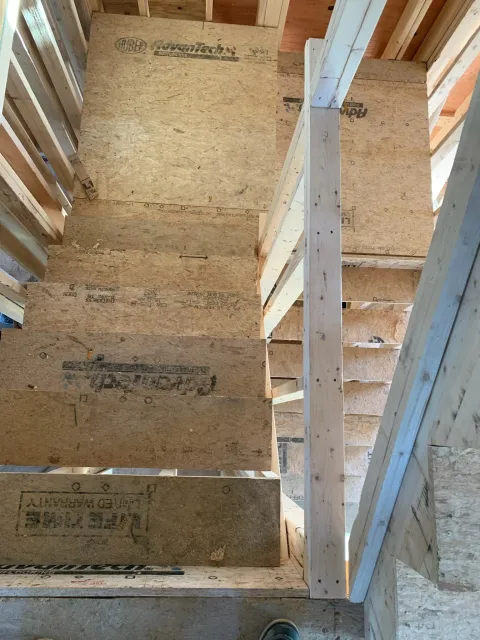 Construction site showing wooden framing and plywood flooring for stairs and upper floor. Scituate, Norwell, Hanover, Hanson, Marshfield, South Shore. Massachusetts Local Construction Company.