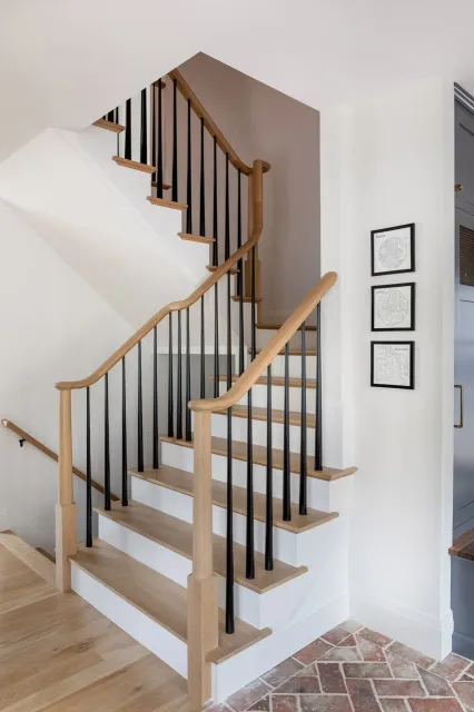 Interior staircase with wooden handrails and black metal balusters in a modern home.