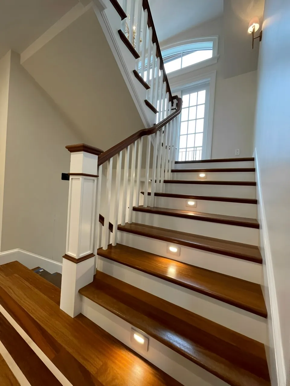 A Staircase Featuring Elegant White Railings And Polished Wooden Steps, Creating A Warm And Inviting Atmosphere.