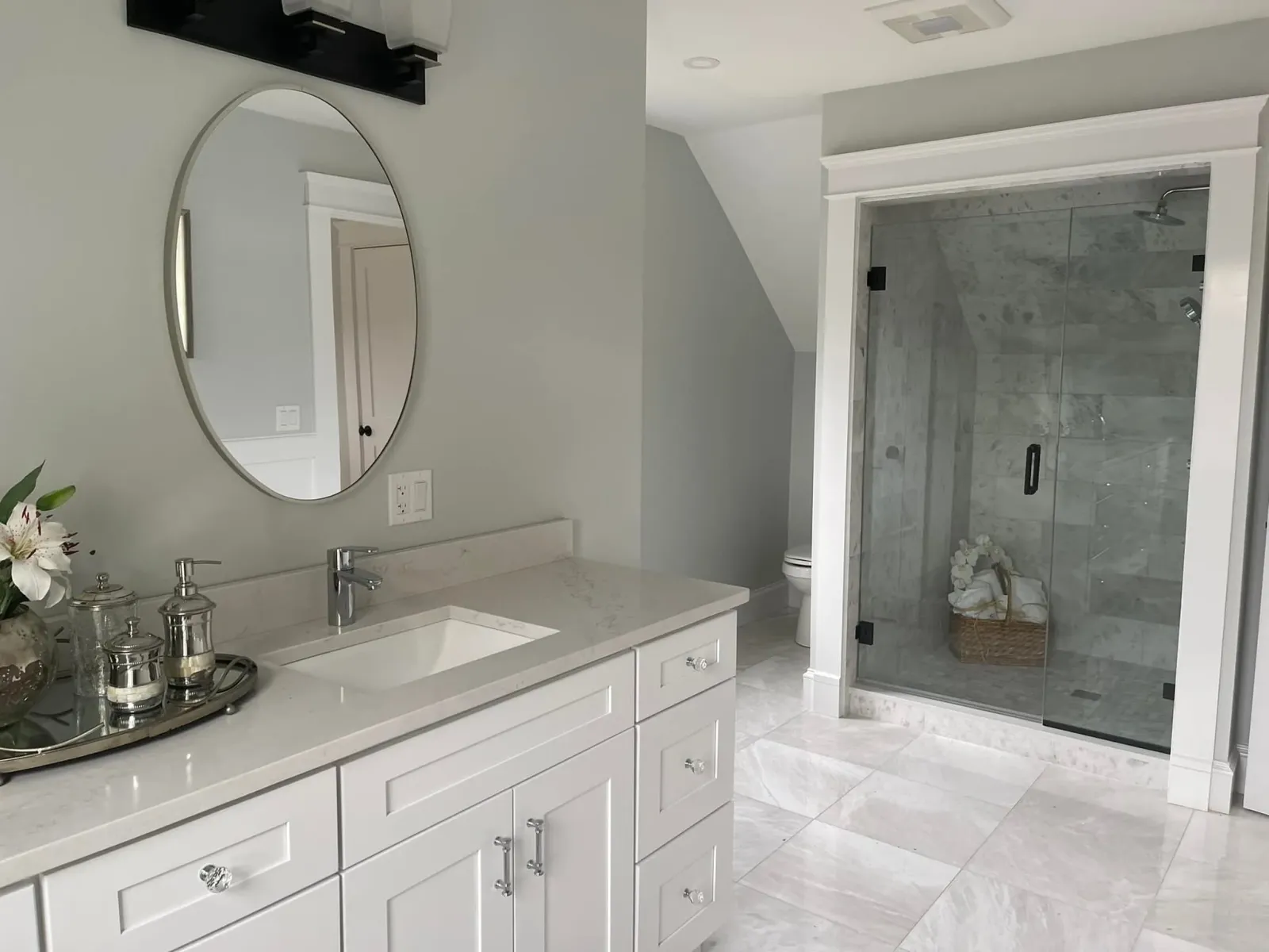 Bathroom with a fitted white vanity, stone top and panel millwork on the wall