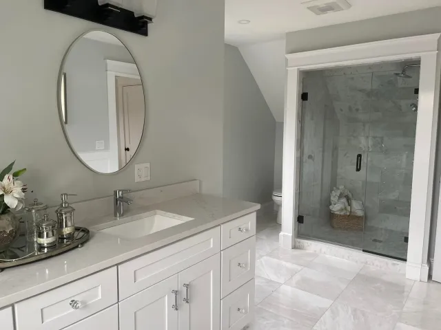 Bathroom with a fitted white vanity, stone top and panel millwork on the wall