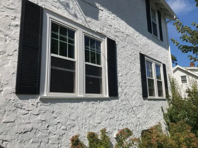 A white house with black shutters on the windows.