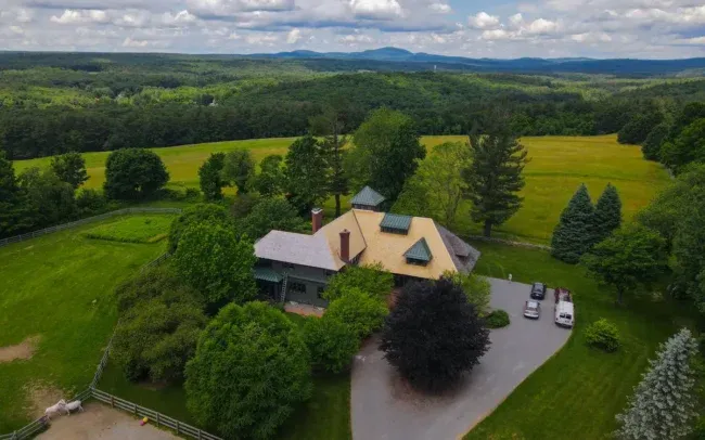 Aerial view of a large countryside house surrounded by green fields and trees