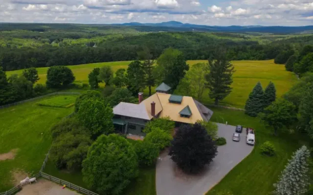 Aerial view of a large countryside house surrounded by green fields and trees