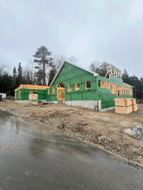 Residential home under construction featuring green ZIP System wall sheathing on a concrete foundation.
