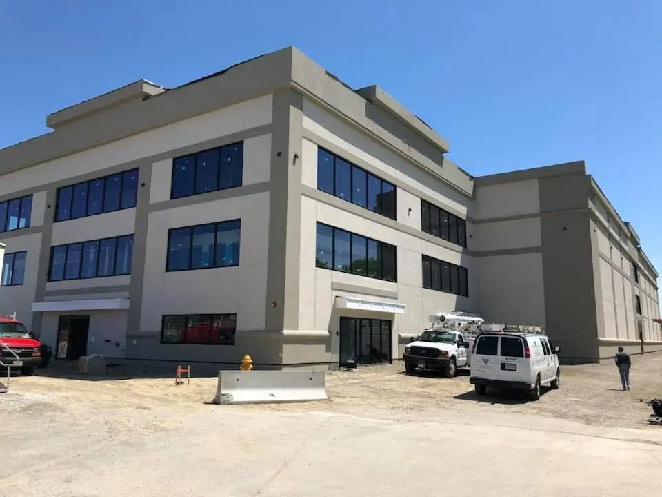 A white van is parked in front of a large building
