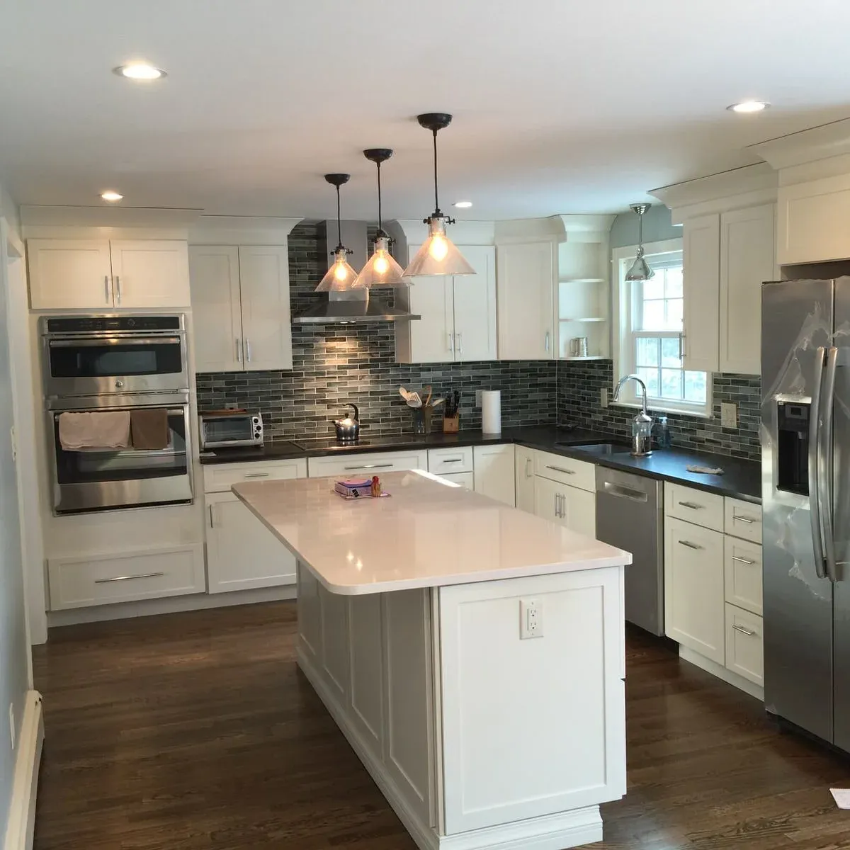 Remodeled kitchen with island and glass-tile backsplash