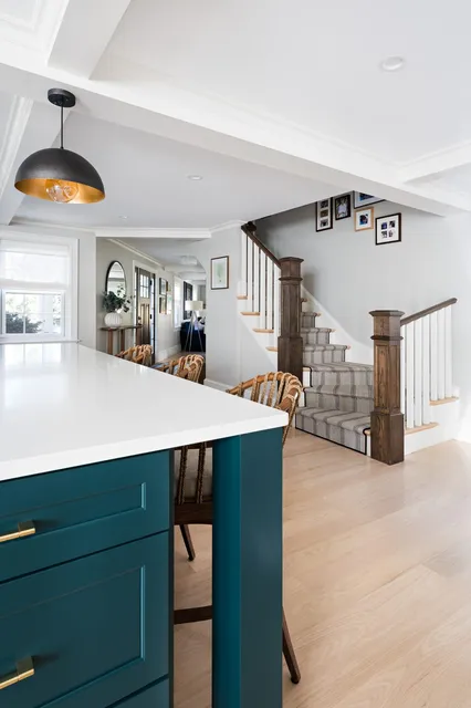 Jerusalem Road kitchen island with teal cabinetry and brass hardware, looking toward the staircase