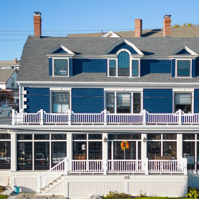 blue house with white fence and lining, large sunroom and porch