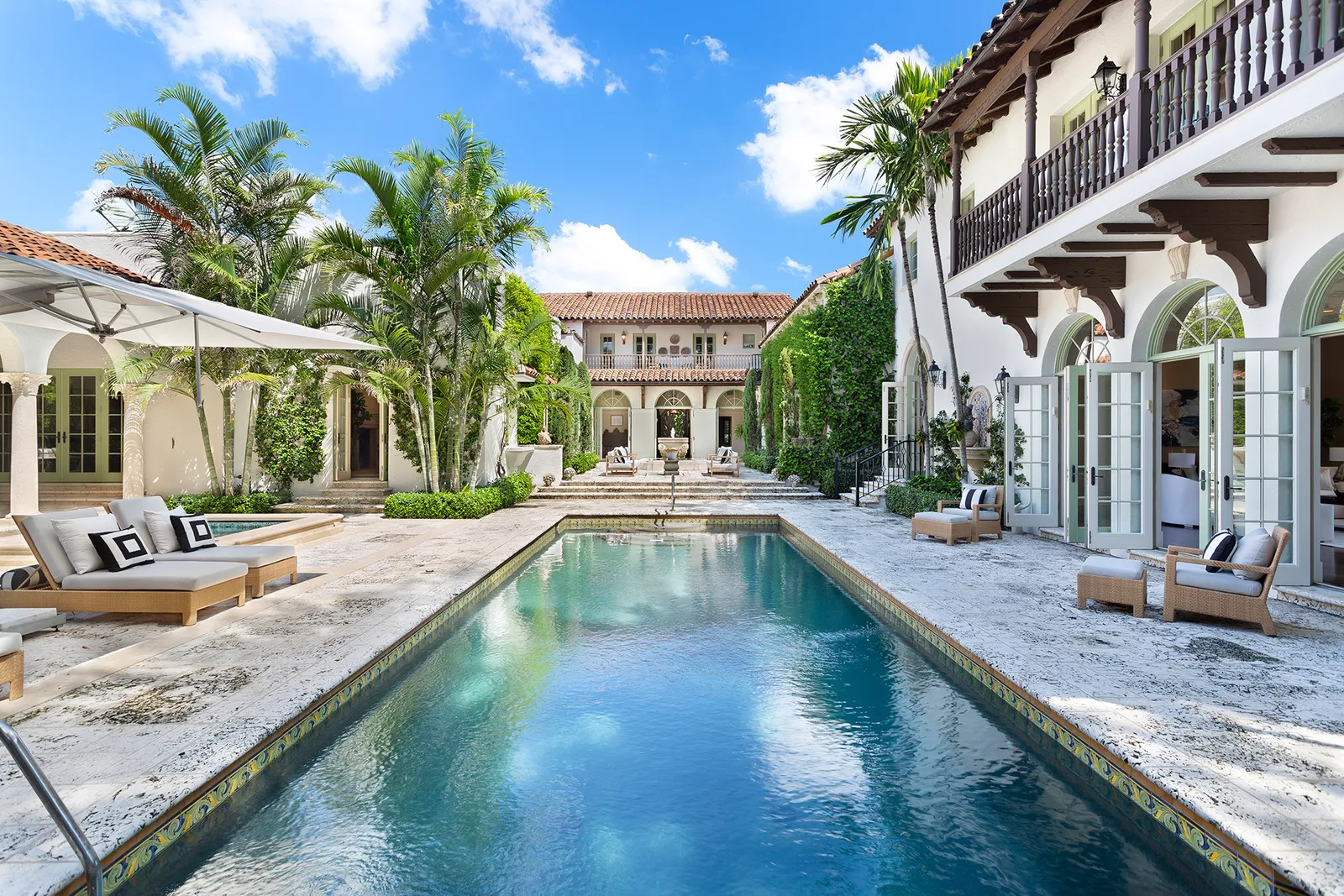 Mediterranean courtyard pool with palms and travertine paving