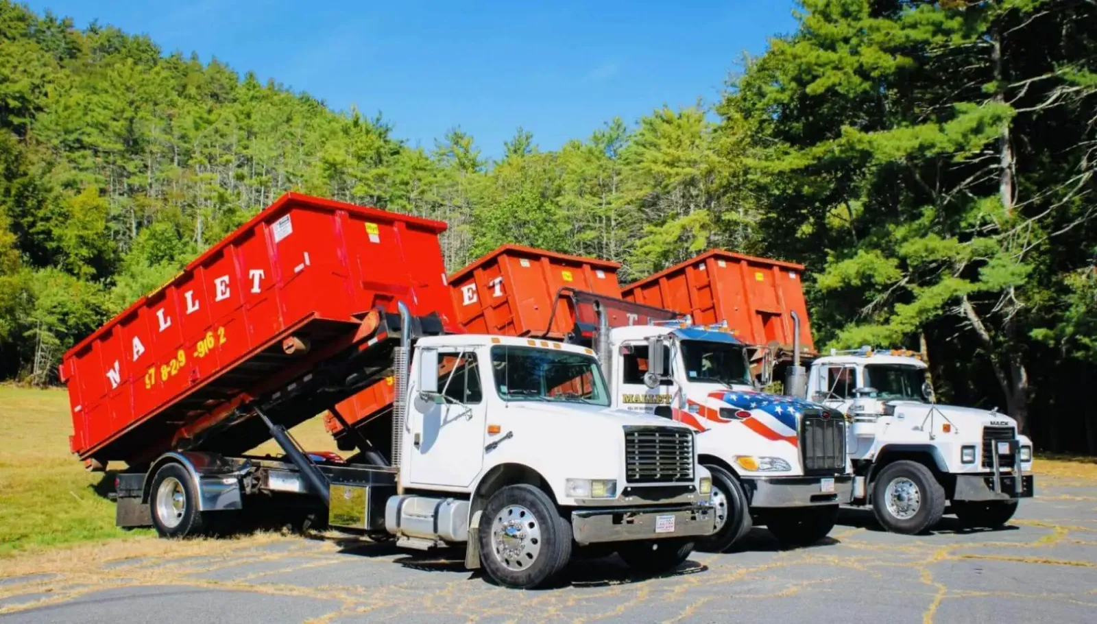 White roll off truck loading red dumpster