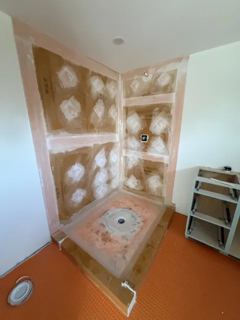 Shower walls and pre-sloped pan sealed with a waterproofing membrane before tile