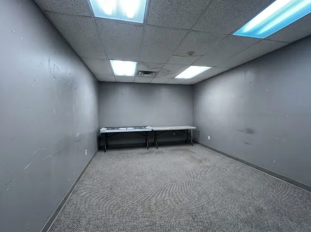 Dated commercial office with gray walls and fluorescent lights — before commercial repaint