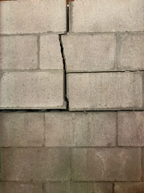 Bowing basement wall with a visible vertical crack near an exterior downspout
