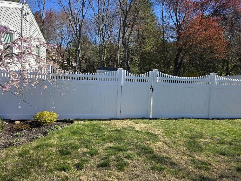 White vinyl privacy fence with picket topper along a back yard