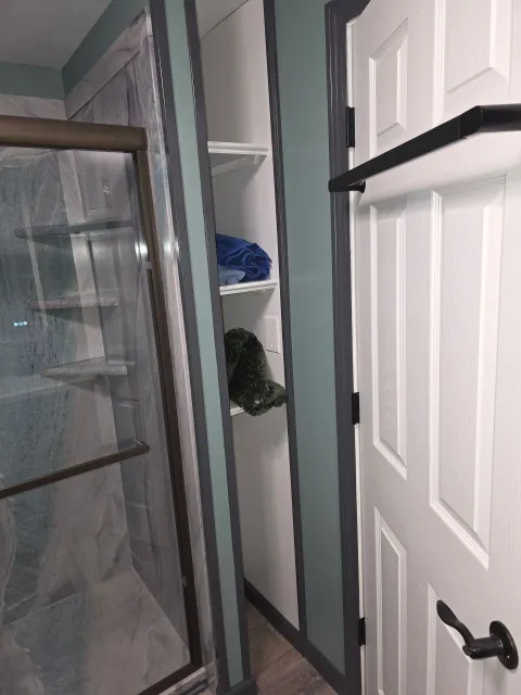 A bathroom with a walk in shower and a closet.