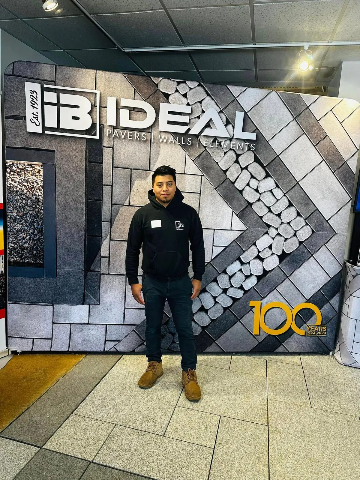 A man is standing in front of a brick wall in a room.