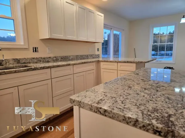 White kitchen cabinets with granite countertops and a matching island.