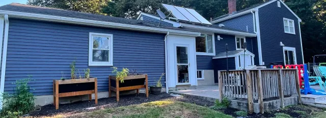 A large blue house with a deck and planters in front of it.