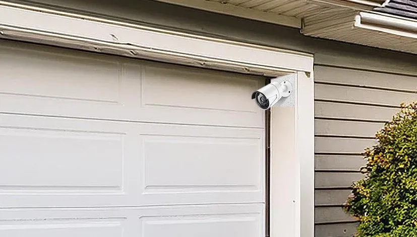 Exterior security camera installed above a garage door