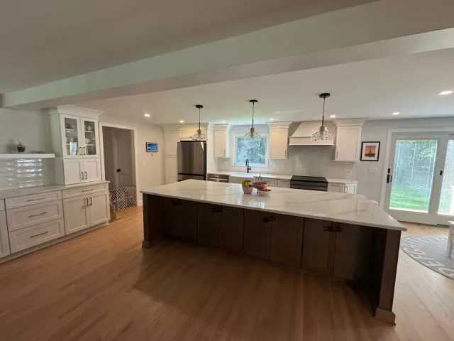 Spacious, light-filled kitchen with large island, white cabinets, and stainless steel appliances.