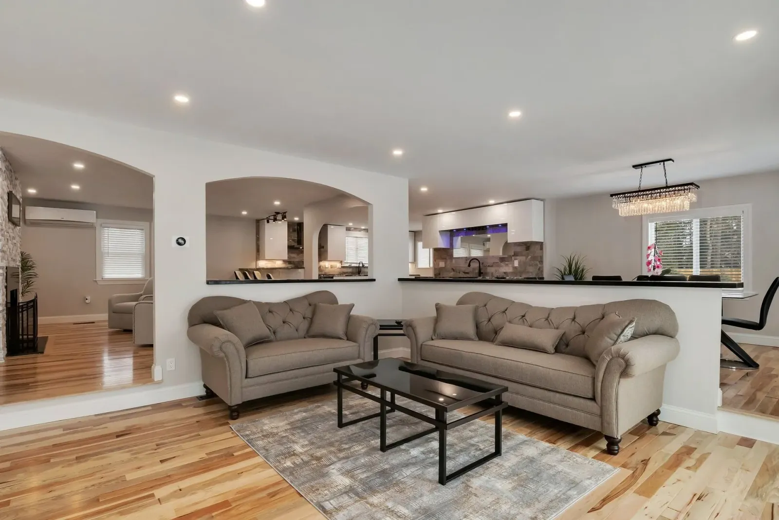 Living room with two gray sofas, black coffee table, and open kitchen view.