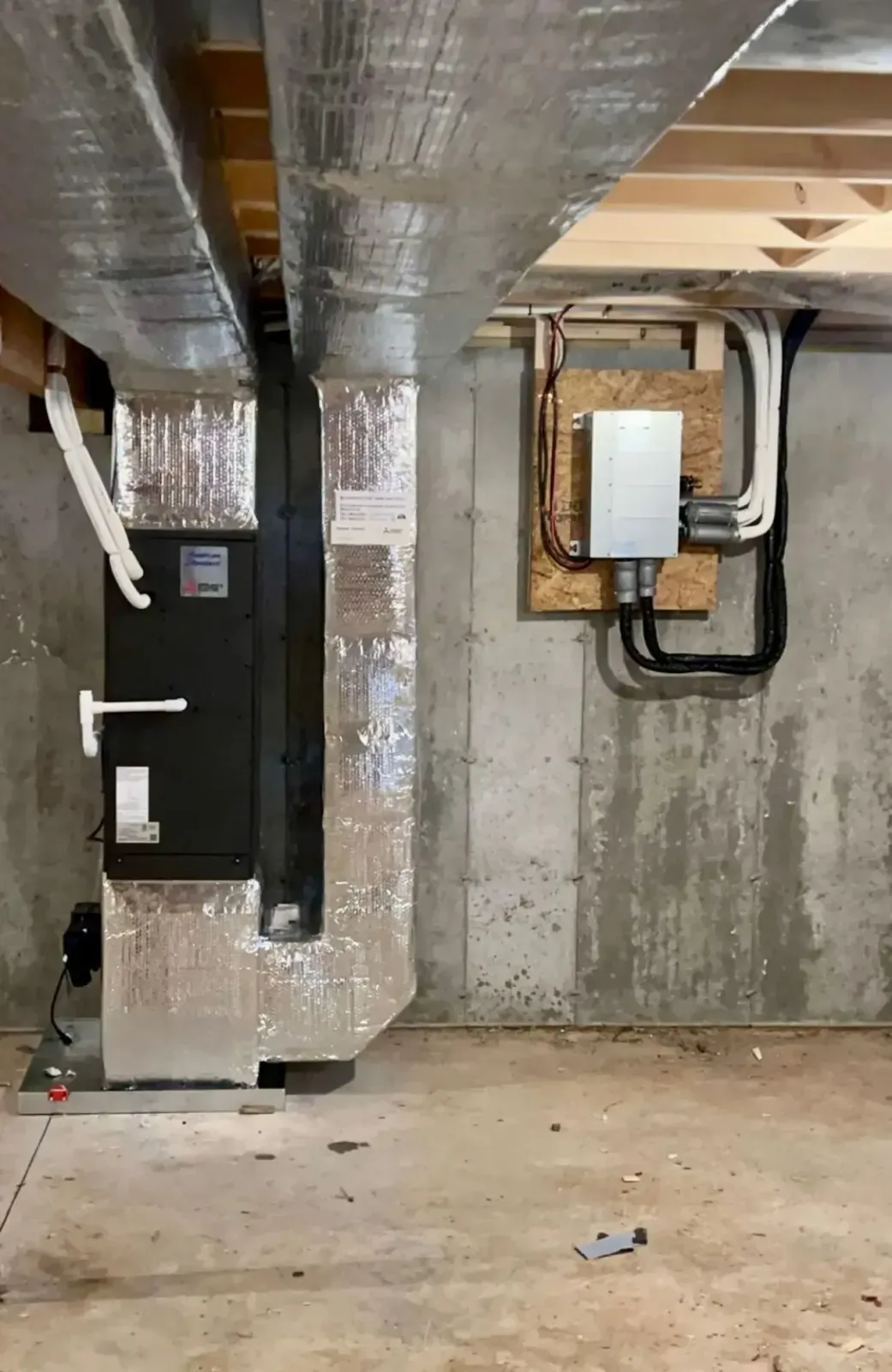 Basement utility room with silver ductwork, furnace, water heater, and concrete walls and floor