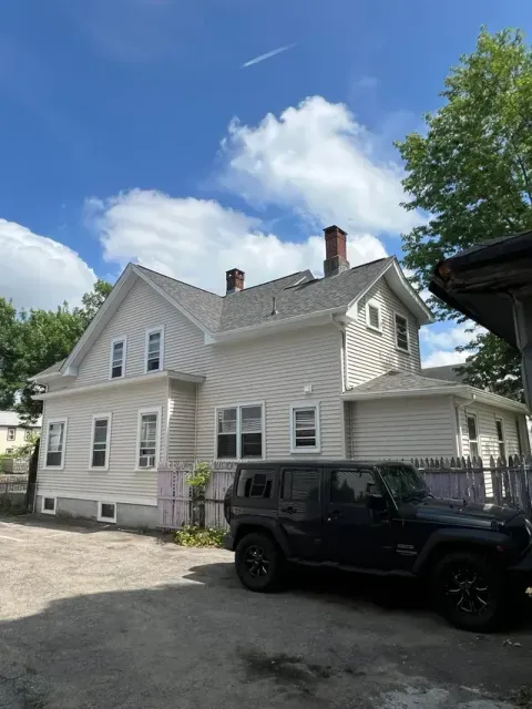 White house with ornate trim under a blue sky, with a black Jeep parked in front