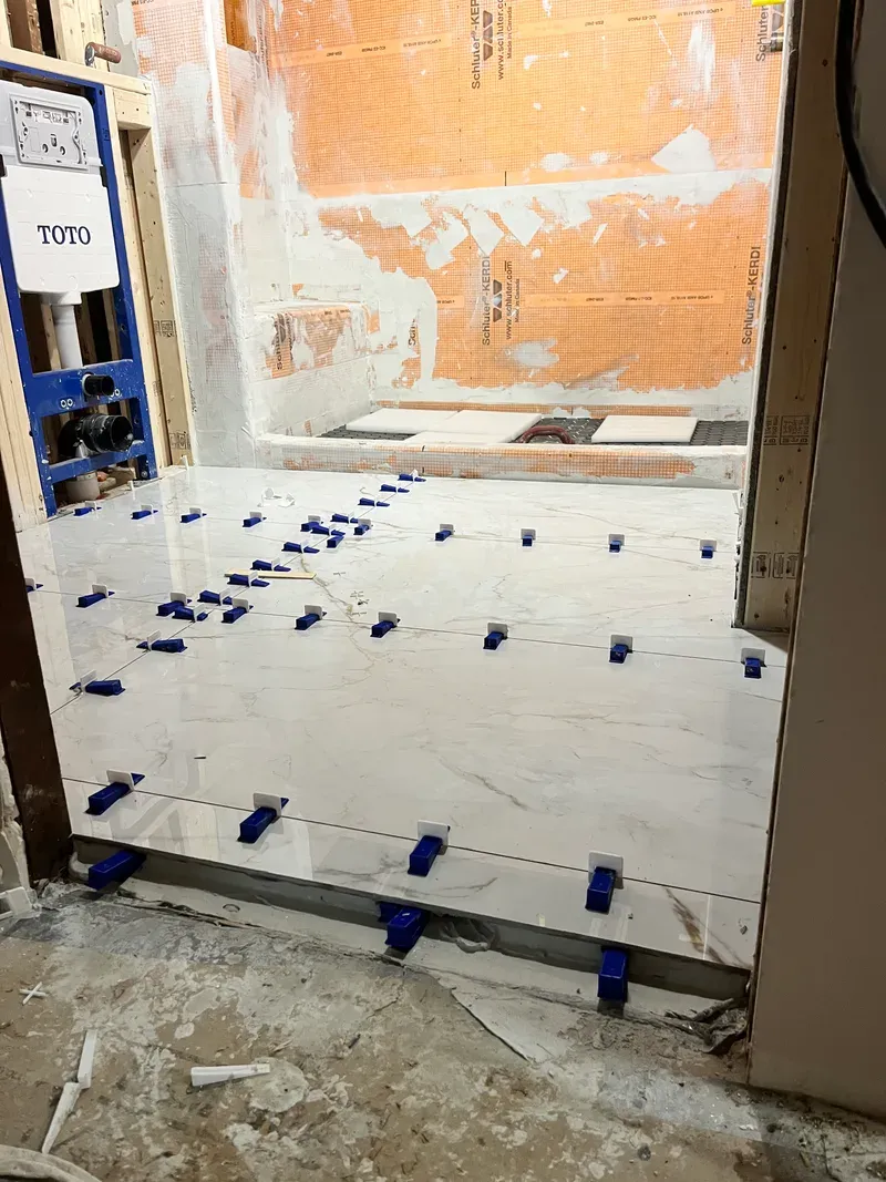 Large-format porcelain floor tile set with leveling clips on every joint for zero lippage