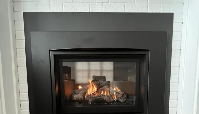 Gas fireplace insert installed in a white brick fireplace in Westbrook ME by the Frechette Chimney Sweeping Team