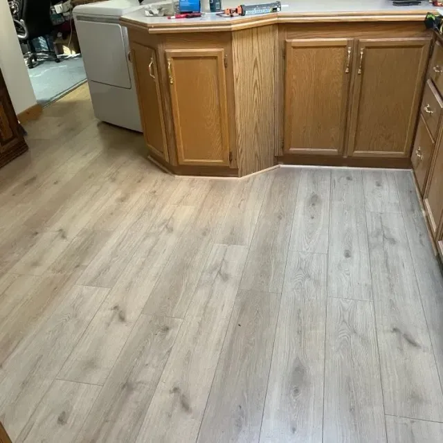 Kitchen with light wood cabinets and gray wood-look flooring, viewed from the floor level