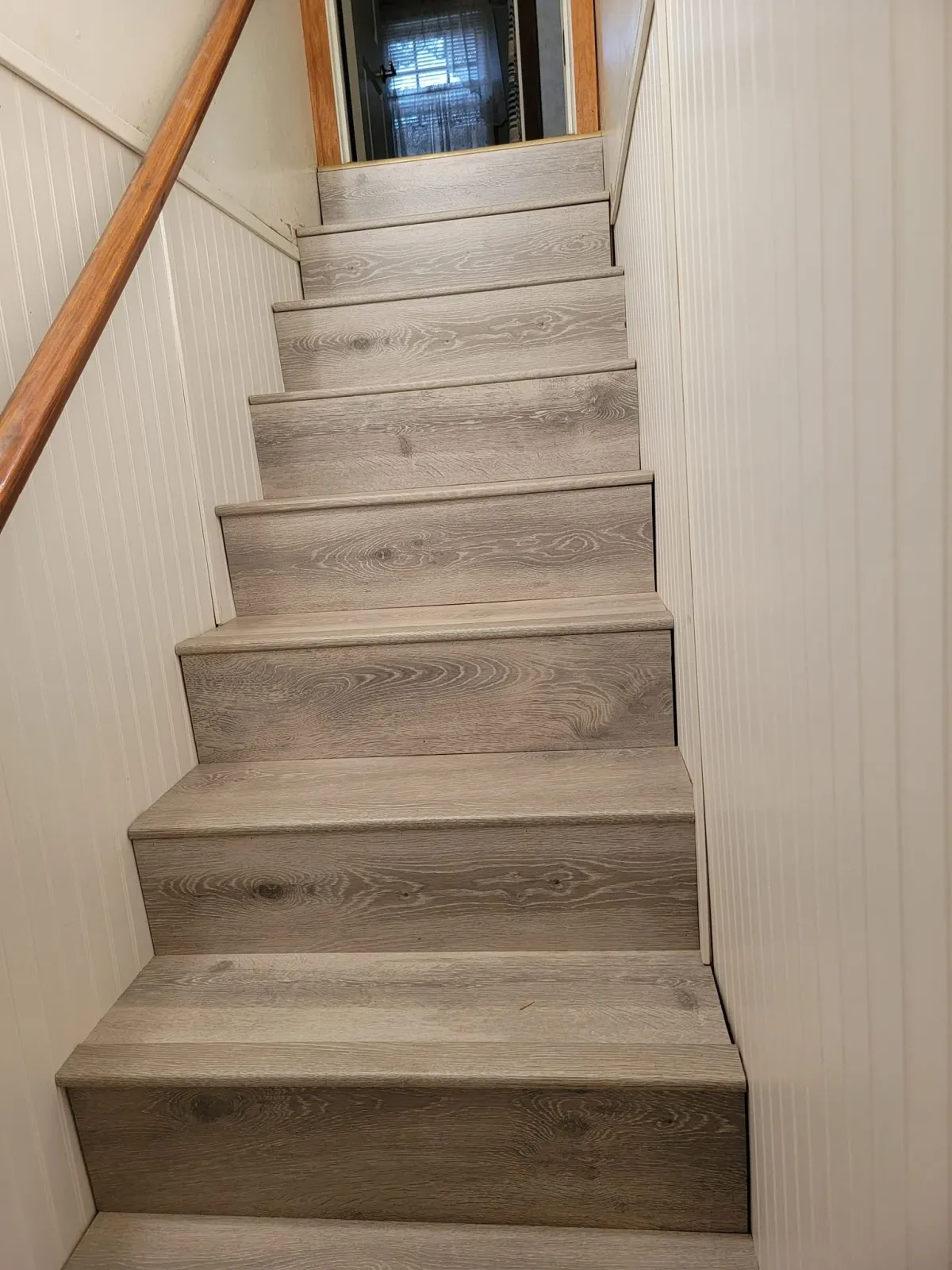 After of previous stairs, with light colored wood flooding installed, and new white beading on the walls.