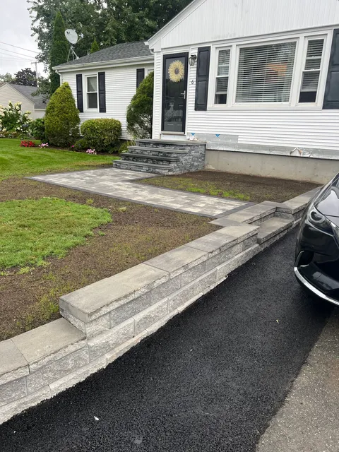 A black car is parked in front of a white house.