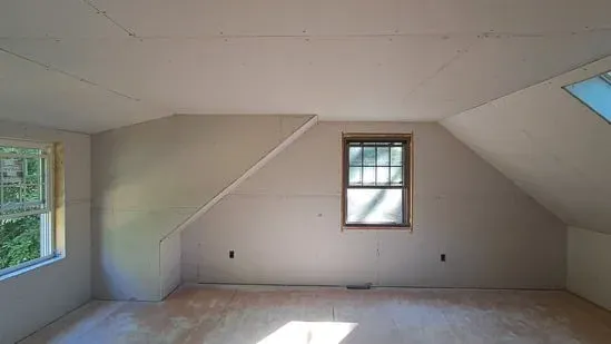 A different angle showing the same attic drywall installation focusing on a dormer window and a sloped ceiling.