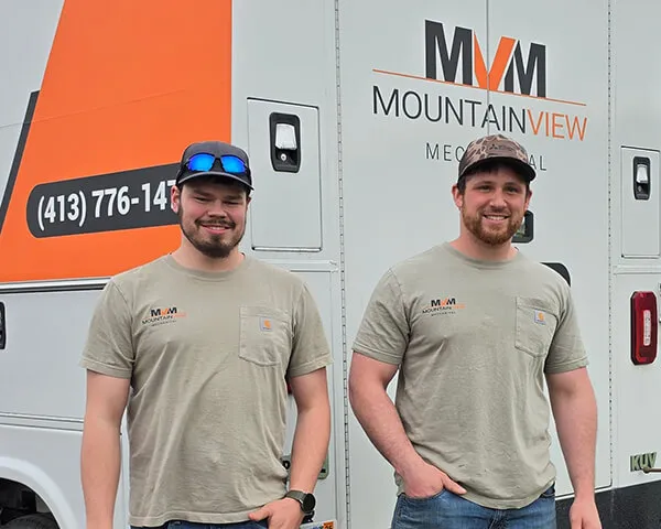 Two men wearing Mountain View Mechanical t-shirts standing in front of a company vehicle with the Mountain View Mechanical logo.