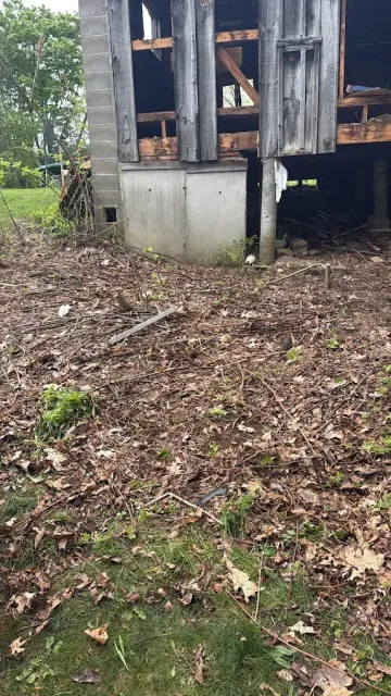 Cleared brush and leaves beside a building foundation